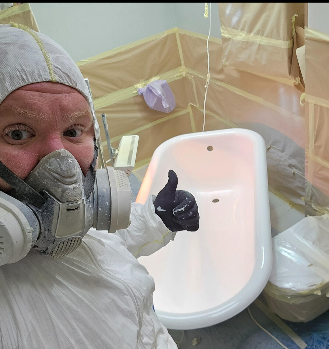photo of glossy baths owner photo of glossy baths re-enamelling owner Seamus with a thumbs up, in ppe, in a room full of masking up and a completed bath in Dudley